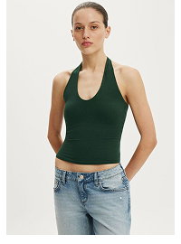 Woman wearing dark green halter crop top and light blue jeans