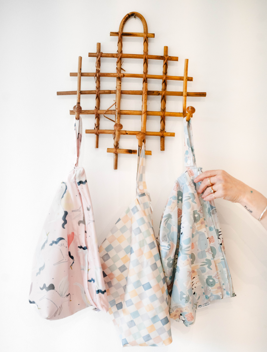 three wet dry bags hanging on a wood wall rack