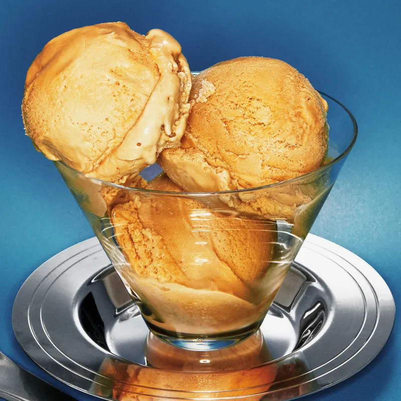Three scoops of coffee ice cream in a glass bowl.