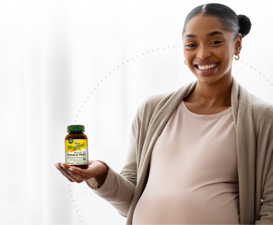 Pregnant woman holding a bottle of MegaFood Baby & Me 2 Prenatal Multi Minis