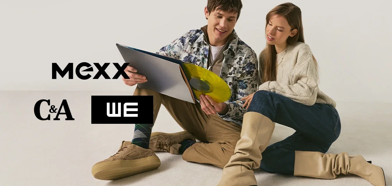 Jonge man en vrouw zitten op de vloer en bekijken samen een gele vinylplaat en de hoes ervan tegen een effen achtergrond.