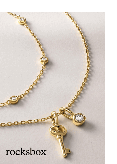 A gold charm necklace with bezel-set diamonds and a sculptural key pendant.