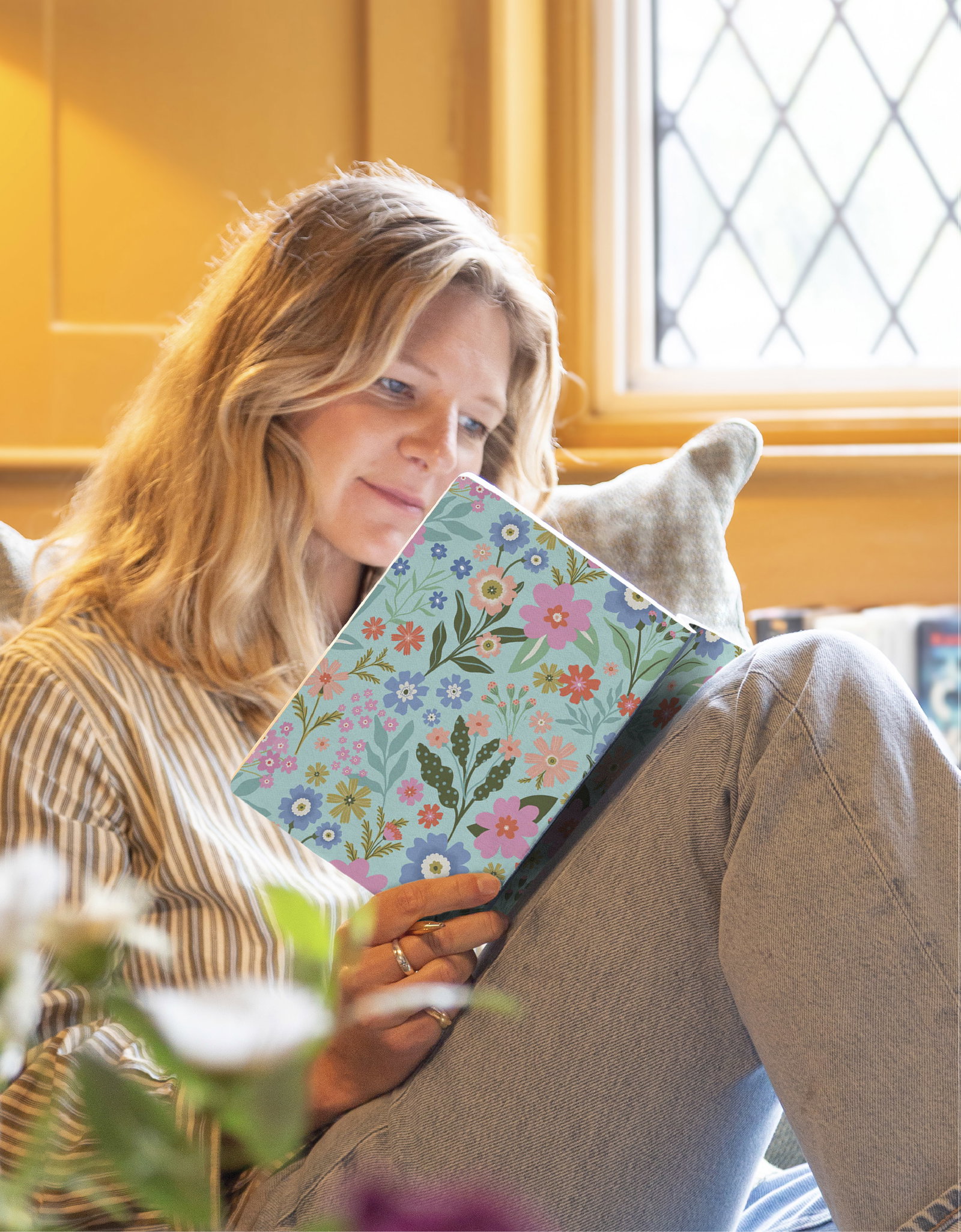 Woman relaxing with a floral Whistlefish notebook, writing by a sunny window.