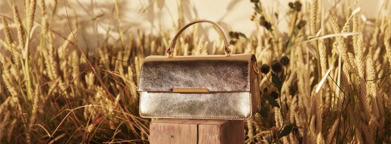 Gold metallic handbag on a post in a golden wheat field