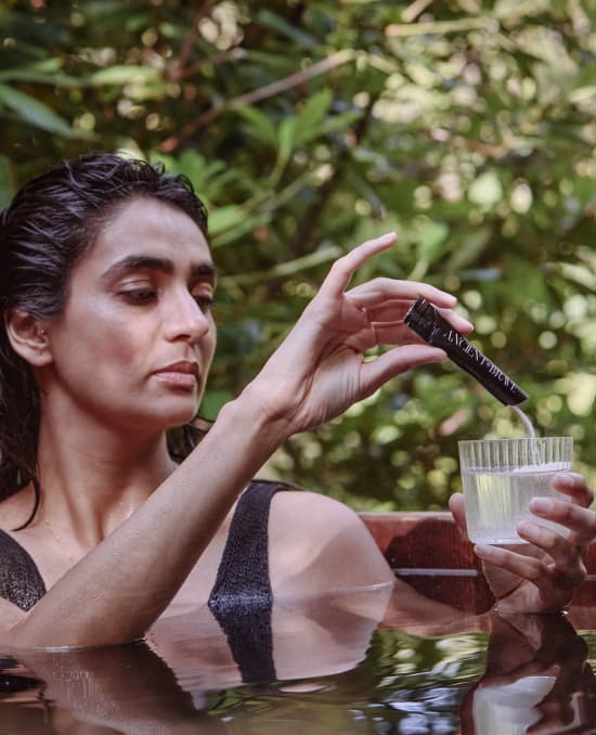 Woman pours sachet of True Collagen into a glass of water