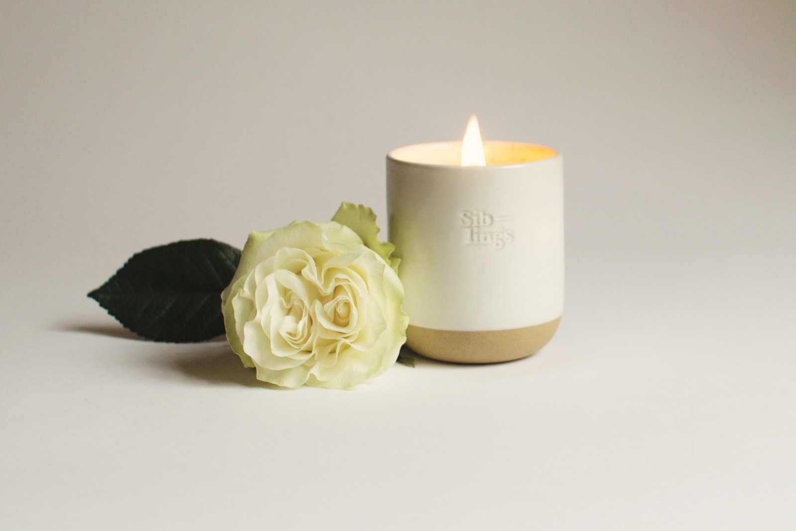 No. 01 Forever Candle sitting with a white rose
