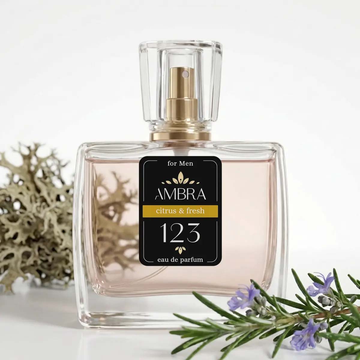 Clear glass bottle of AMBRA men's eau de parfum 'Citrus & Fresh 123' with sprig of rosemary flowers and lichen backdrop