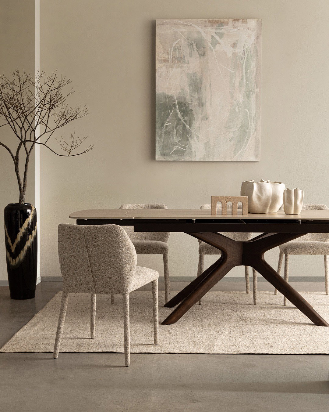Modern neutral-toned dining room with dark wooden X-base table, beige upholstered chairs, abstract wall art and ceramic vases
