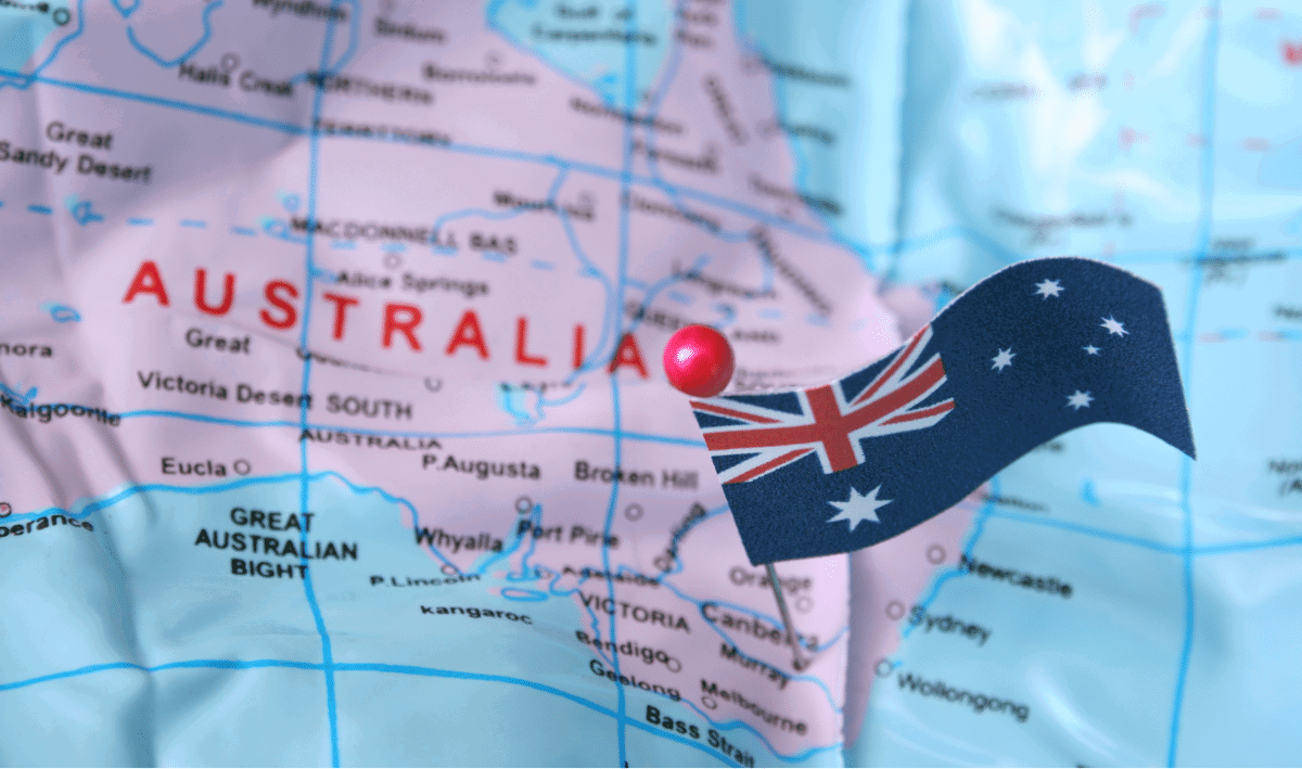 A close-up of a map showing Australia with a red pin marking a location and an Australian flag positioned nearby.