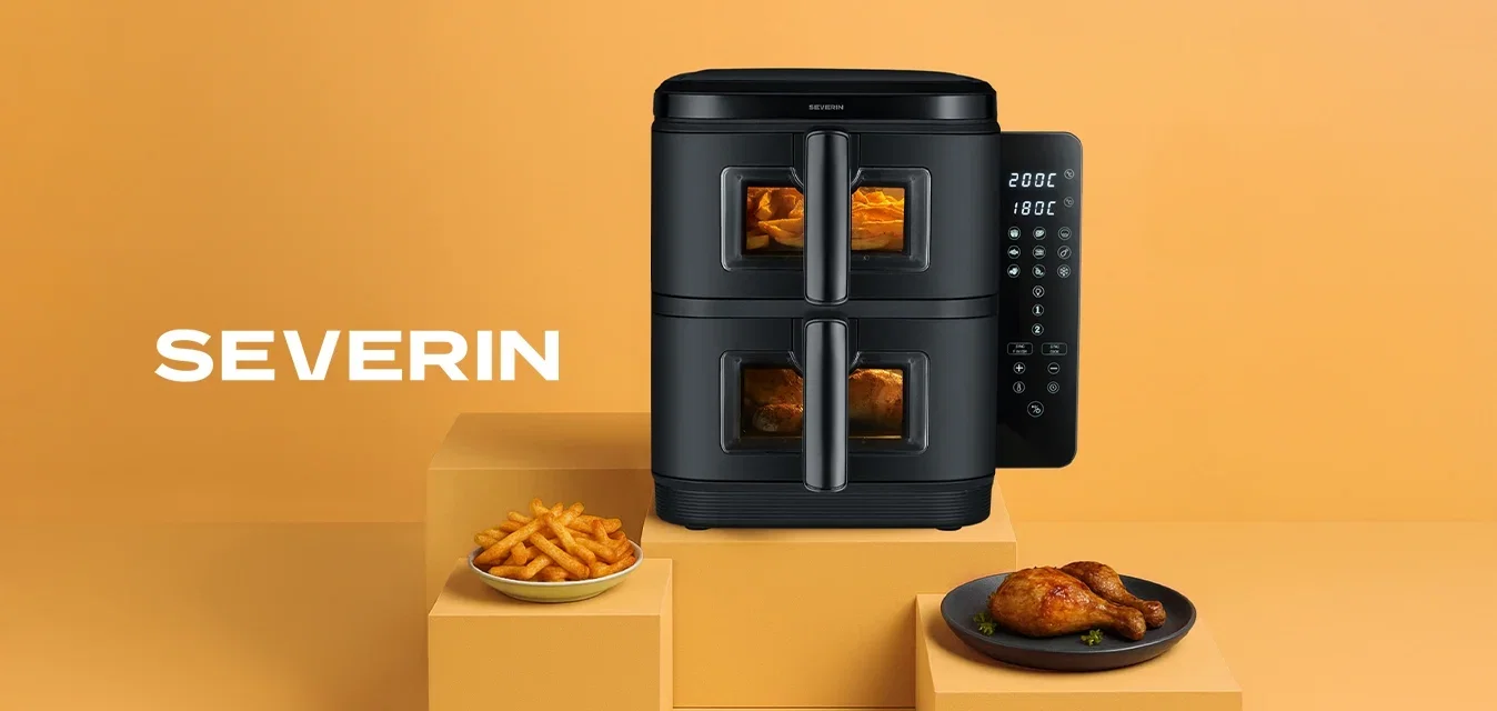 Freidora de aire negra con dos compartimentos, controles digitales en un lado, colocada sobre un fondo naranja claro, con patatas fritas y pollo en platos.