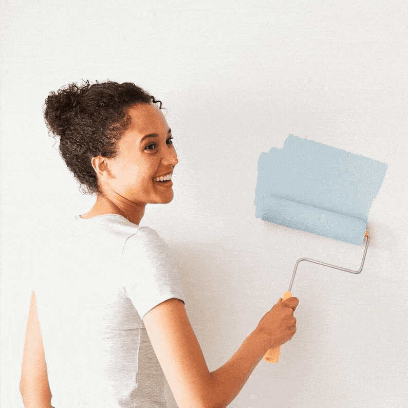 Woman rolling blue paint color on wall