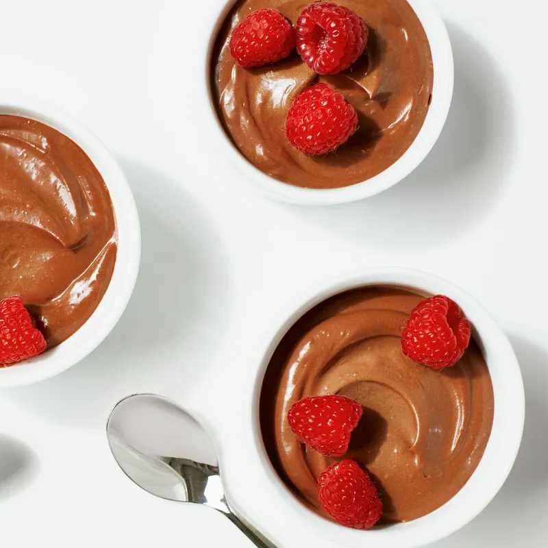 Four bowls of mousse made from silken tofu and bittersweet chocolate chips topped with raspberries.