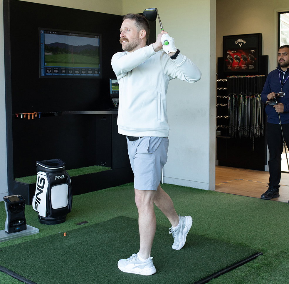 golfer testing new clubs in fitting bay