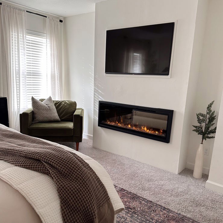 Modern bedroom with TV and electric fireplace.