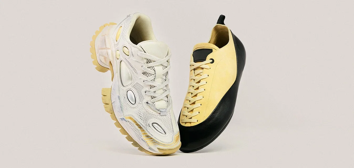 Due scarpe fluttuanti: a sinistra una sneaker bianca e beige chunky, a destra una scarpa allacciata nera e gialla elegante.