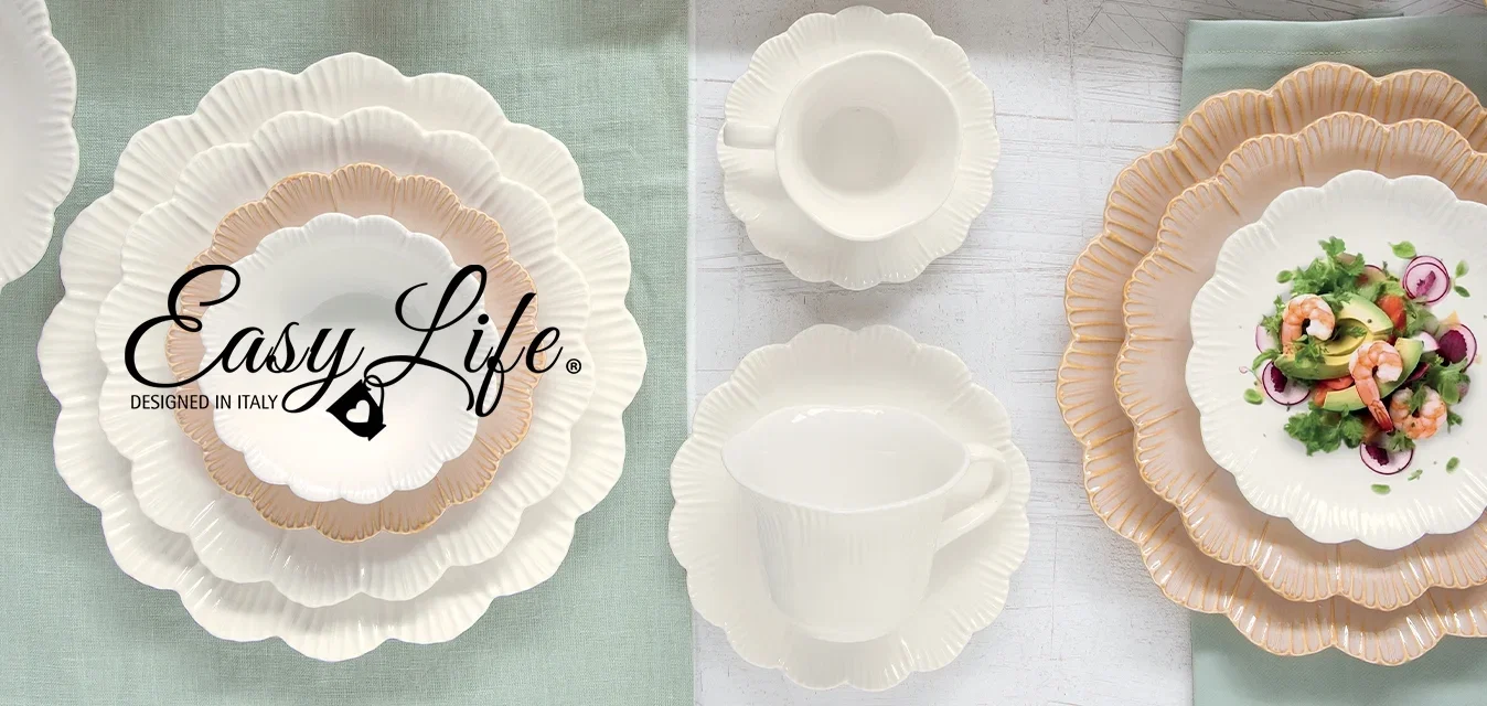 Witte en beige keramische borden, kommen en kopjes met gekartelde randen, gerangschikt op groene en witte achtergronden, met een salade op één bord en een takje groen.