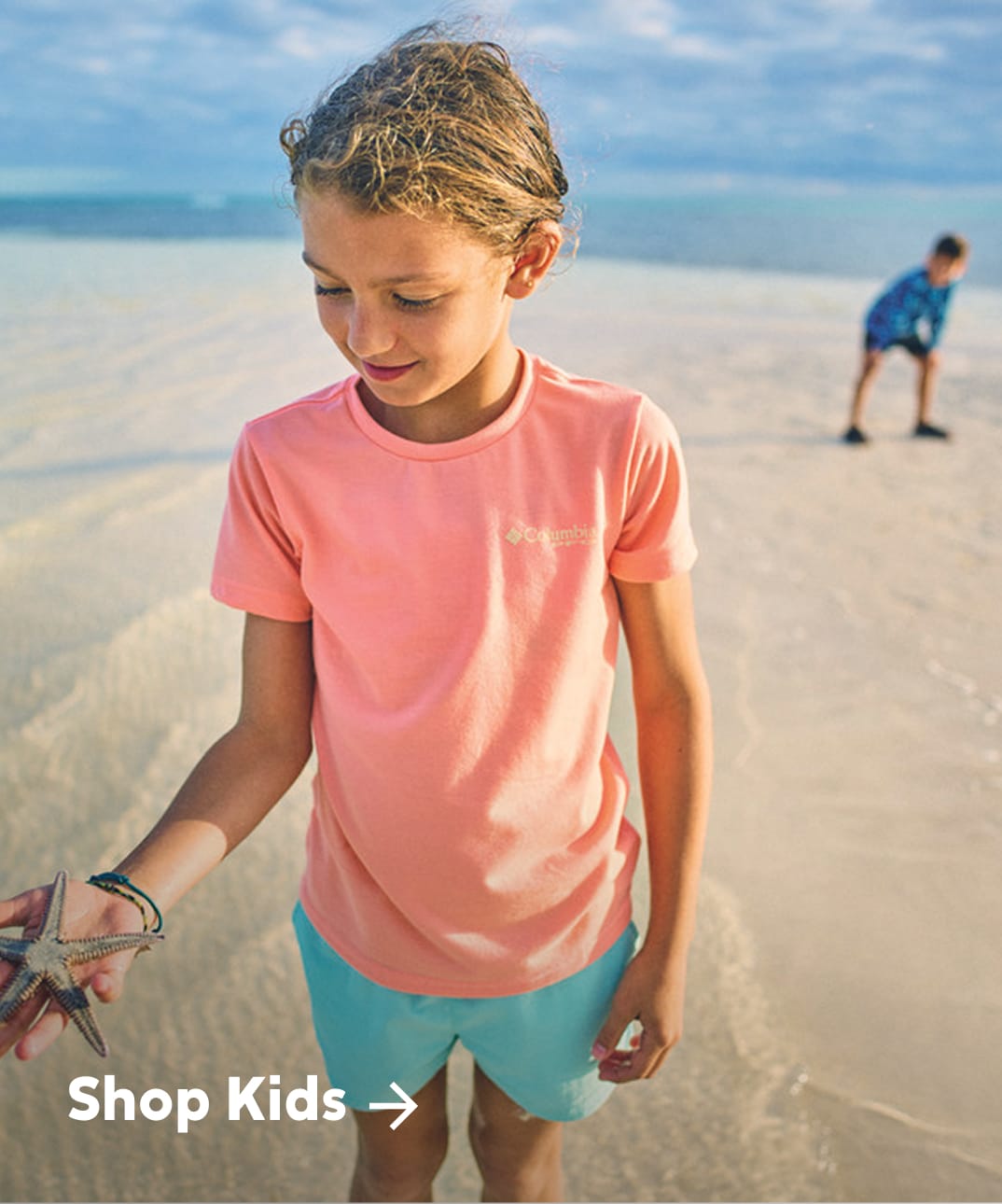 Two little kids exploring a beach with text: Shop Kids