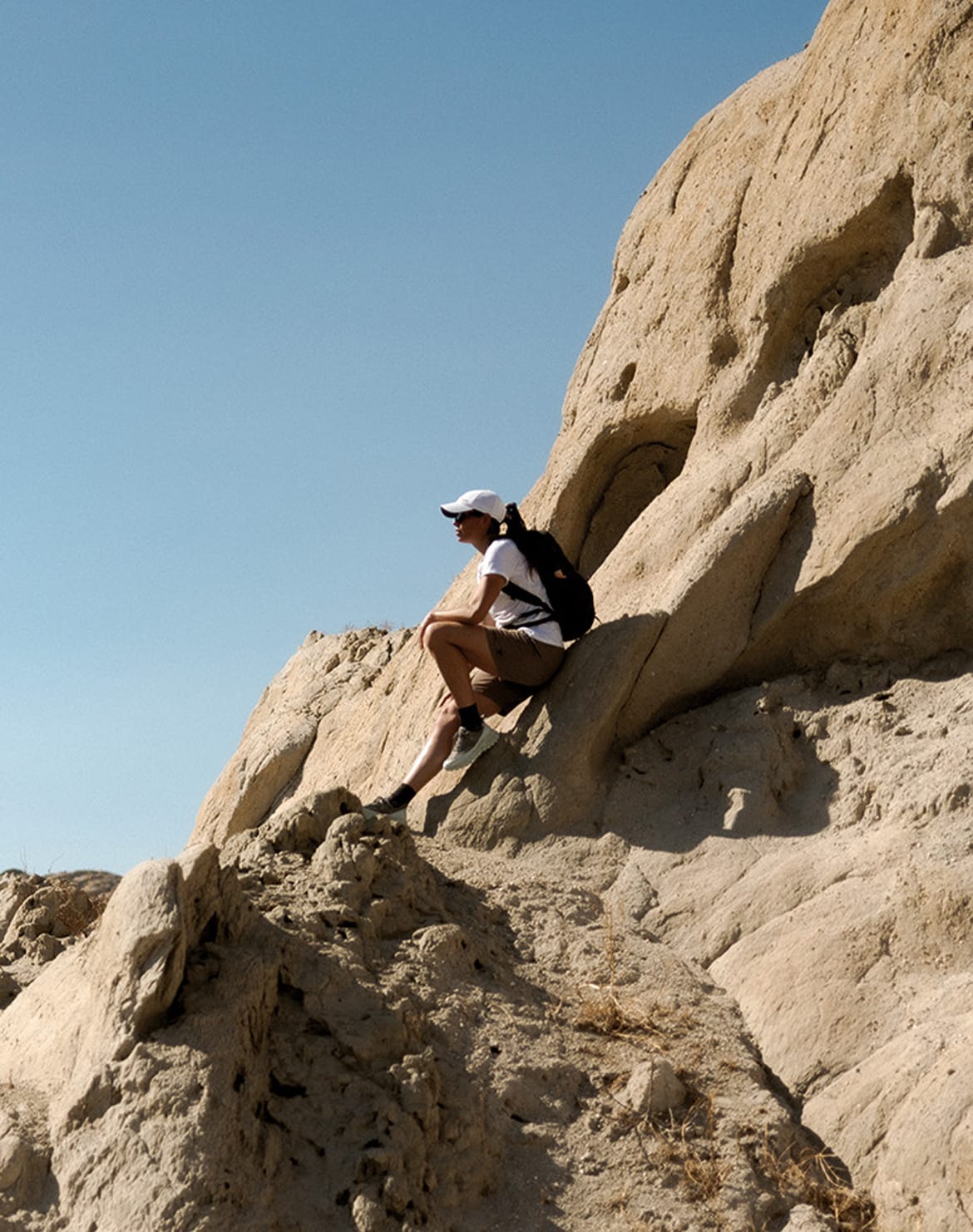 A woman sitting in a rocky landscape with blue sky. 