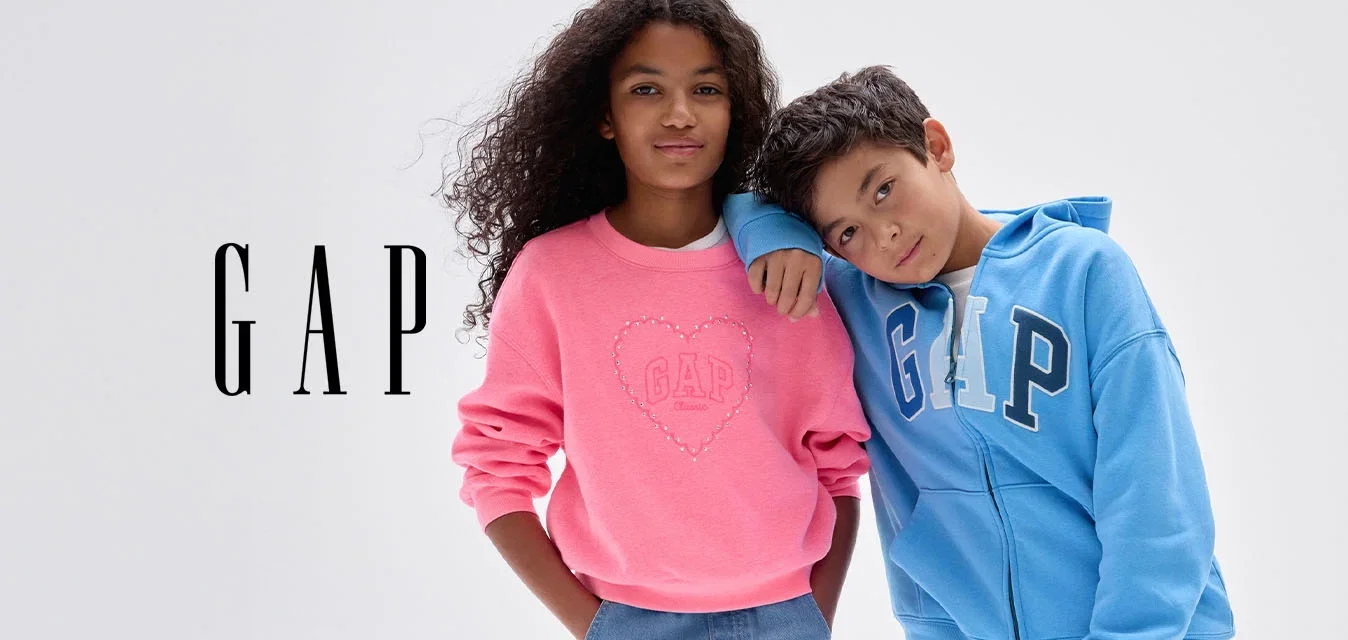 Deux enfants se tiennent ensemble ; une fille en sweat-shirt rose et jean large, un garçon en sweat à capuche bleu GAP et jean, appuyant sa tête sur l'épaule de la fille.