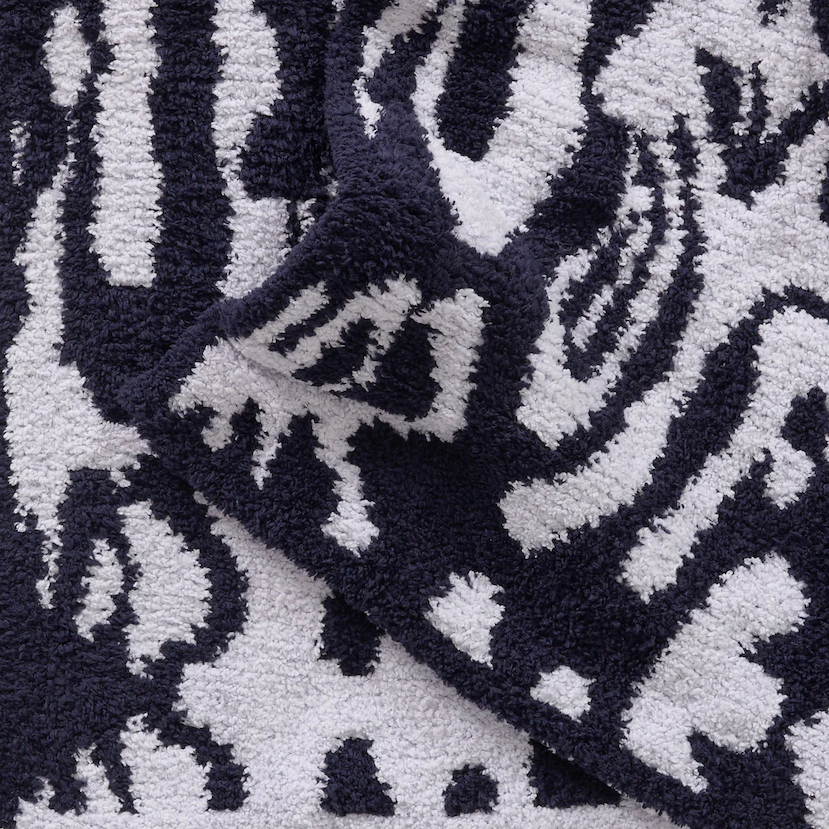 Close-up of a plush Kashwére throw in dark navy and ice blue with an oversized damask pattern, showcasing its soft texture and folded corner.