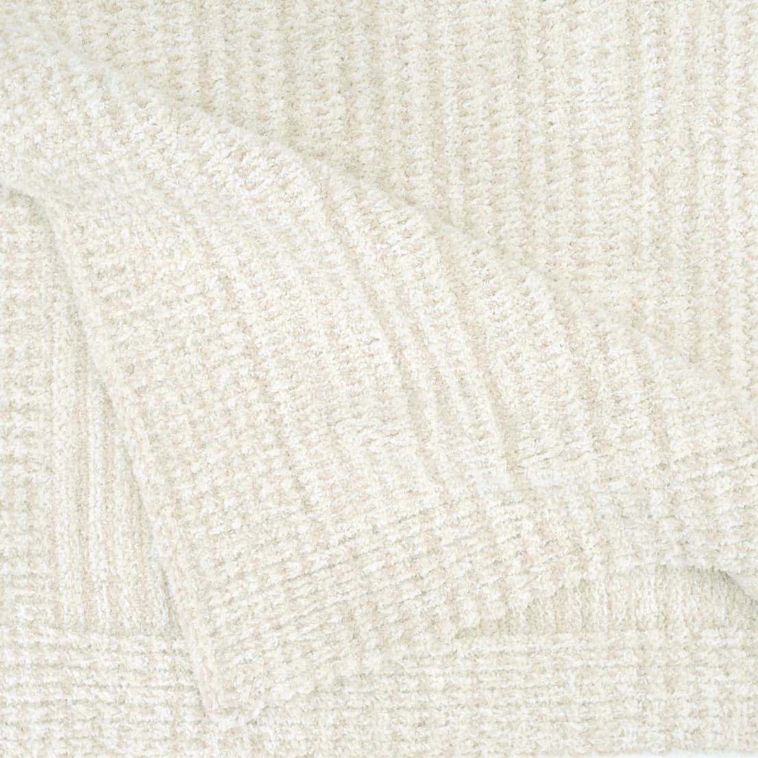 Close-up of a plush Kashwére throw in soft cream, linen, and wheat heathered stripes, highlighting its textured knit and cozy, folded edge.