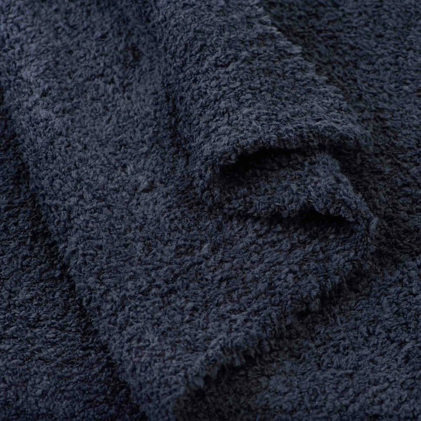 Close-up of a solid dark navy Kashwére throw, highlighting its plush texture and soft, gathered folds.