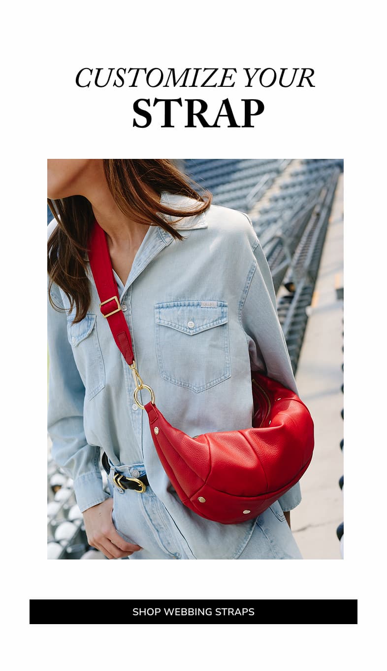 Model wearing the Hammitt Erica Med in Chili Red pebbled leather with a matching webbing strap and the message "Customize Your Strap."