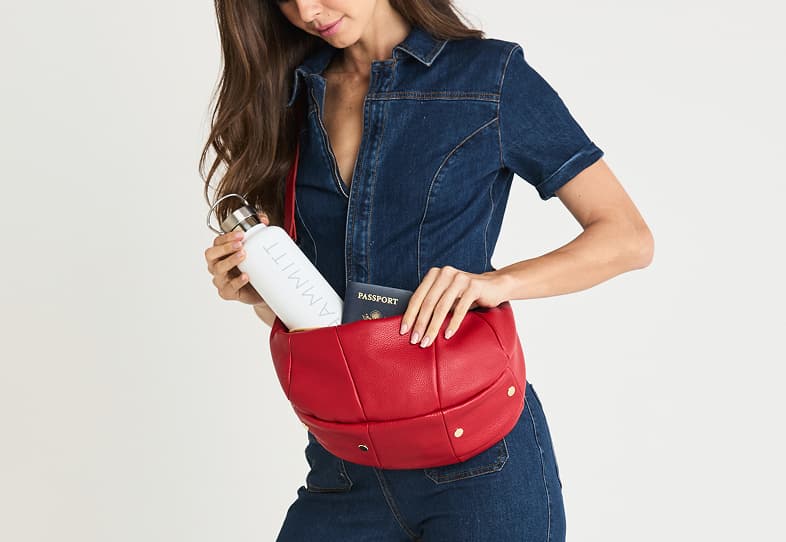 Model filling the Hammitt Erica Med in Chili Red pebbled leather with everyday essentials.