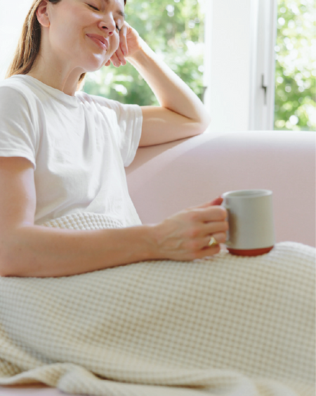 Woman relaxing with coffee and a merino blanket