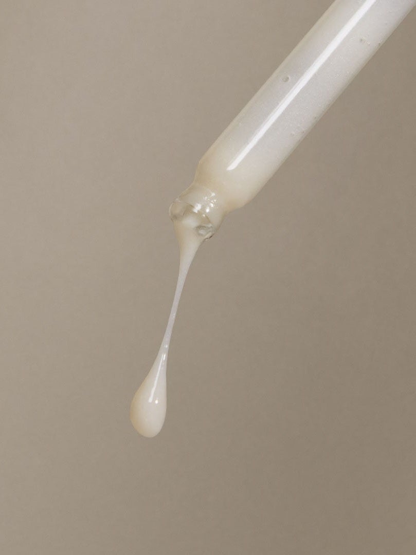 close up of pipette with serum dripping out with one droplet falling
