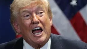 Donald Trump speaks, mouth wide open.