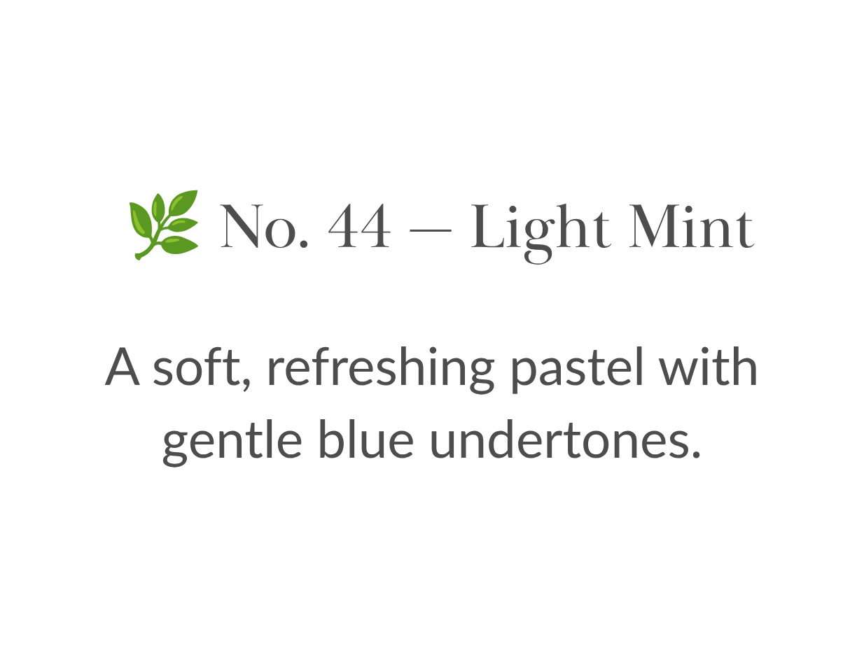 Bottle of pale mint-green nail polish resting in green grass outdoors.