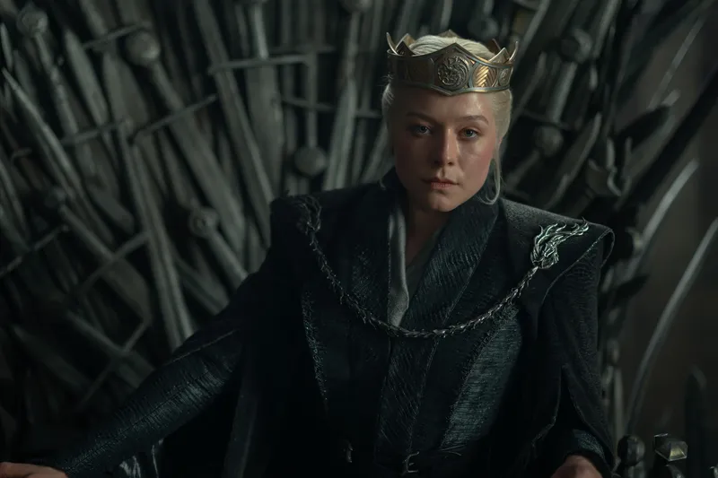 Emma D'Arcy as Rhaenyra Targaryen in a still from %22House of the Dragon%22 season three, sitting on the throne with a crown. 