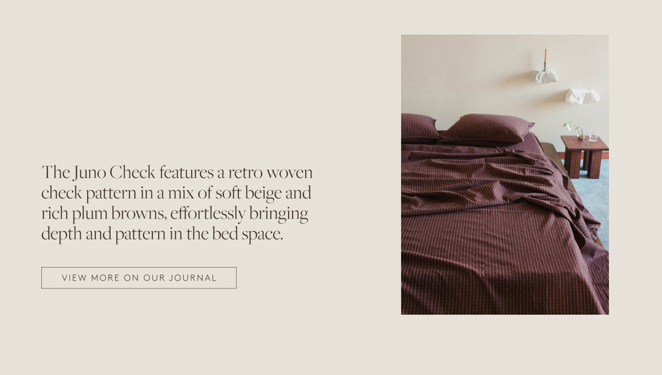 A bed dressed with the maroon check sheet set next to a wooden nightstand