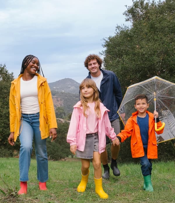 A family in colorful totes rain gear walk together