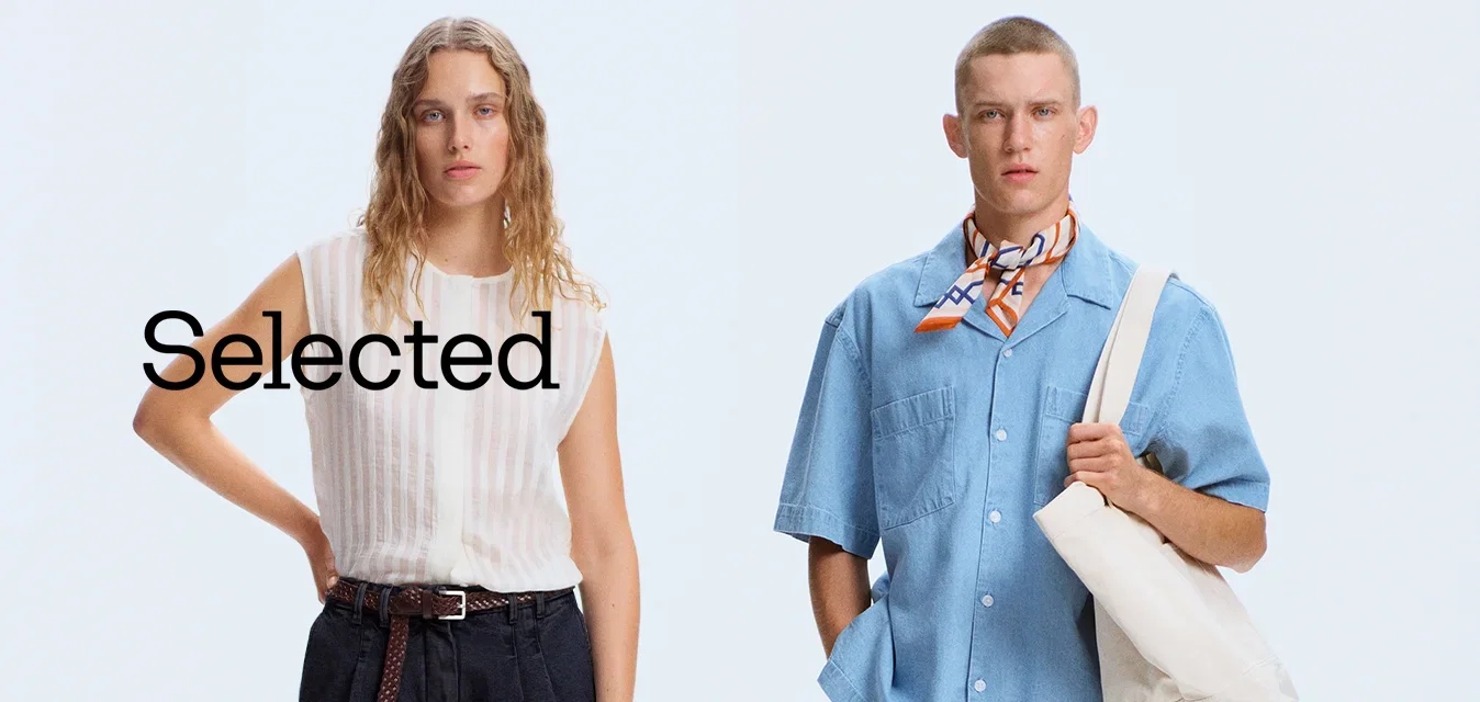 Twee modellen staan naast elkaar; de ene draagt een mouwloze witte blouse en zwarte broek, de andere een blauw hemd met korte mouwen, een neksjaal en een witte tas.