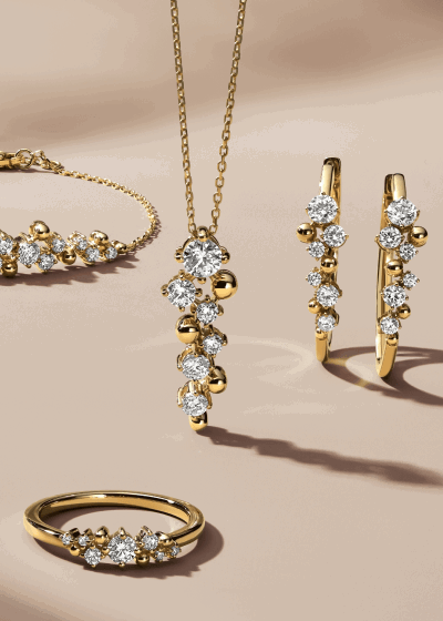 A gold diamond jewelry set featuring a ring, pendant necklace, earrings and a bracelet.