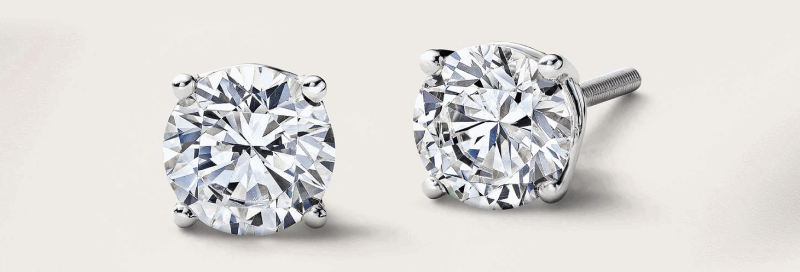 A pair of round diamond stud earrings in a classic four prong setting.