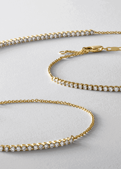 Two gold tennis bracelets set with round brilliant diamonds.