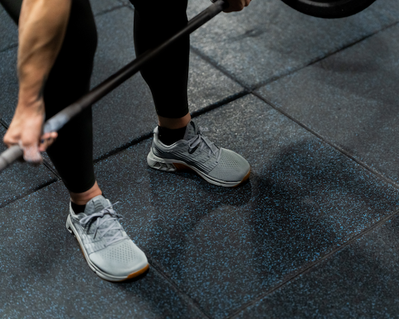 A close up of F-LITE MAX shoes helping stabilise an athlete lifting a barbell