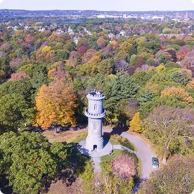 Aerial view of a hilltop observation tower amid fall foliage near Boston