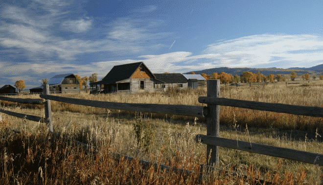 Barn and a wooden fence on a plot of land.