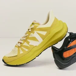 Zapatilla de correr amarilla y zapatilla negra sin cordones con detalles naranjas colocadas una al lado de la otra sobre un fondo liso y claro.