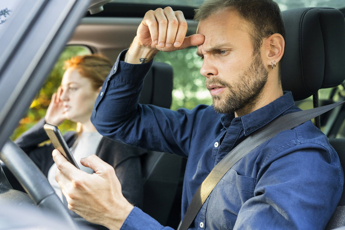 Un homme circonspect devant son smartphone dans sa voiture