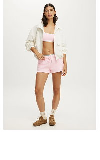 Woman wearing cream blazer and pink shorts with brown loafers