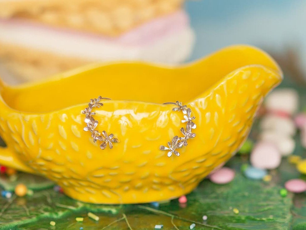 Alex Monroe Sprouting Rosette Hoop Earrings displayed in a yellow ceramic jug.