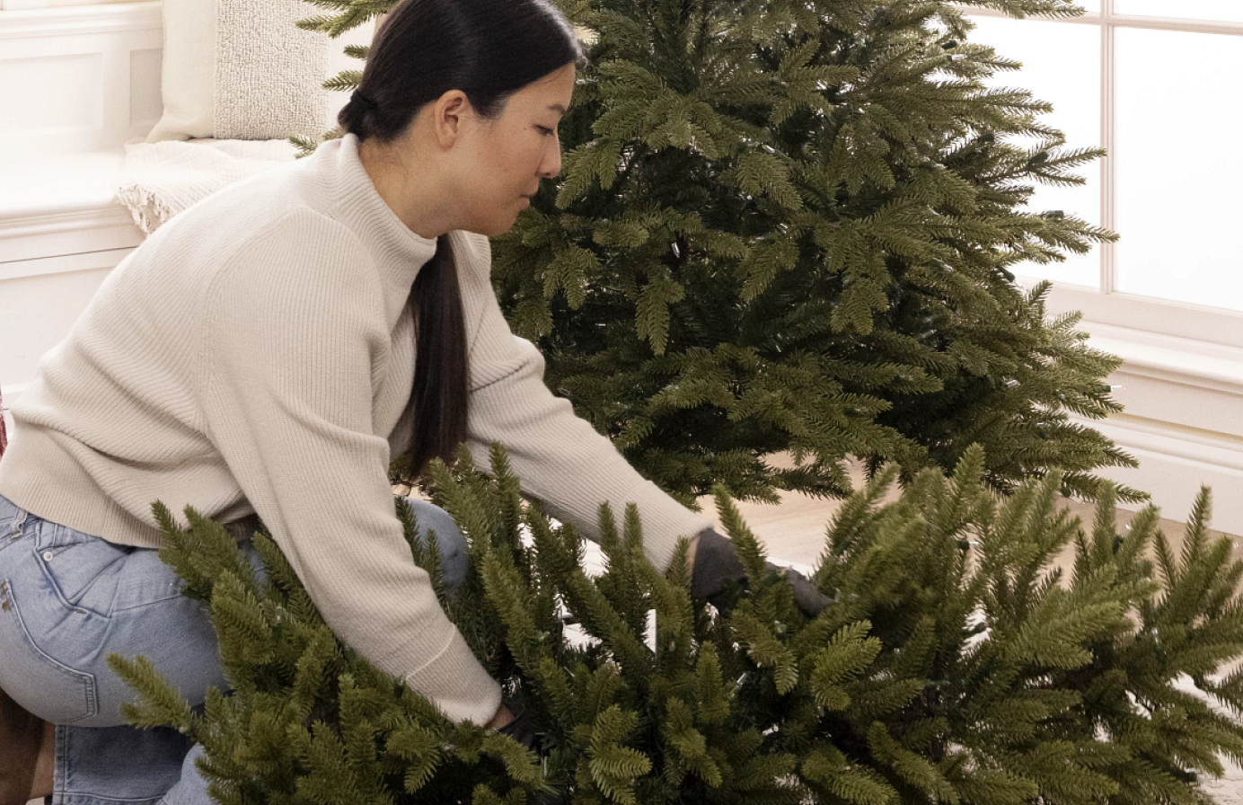 Woman assembling the lower branches of an artificial Christmas tree.