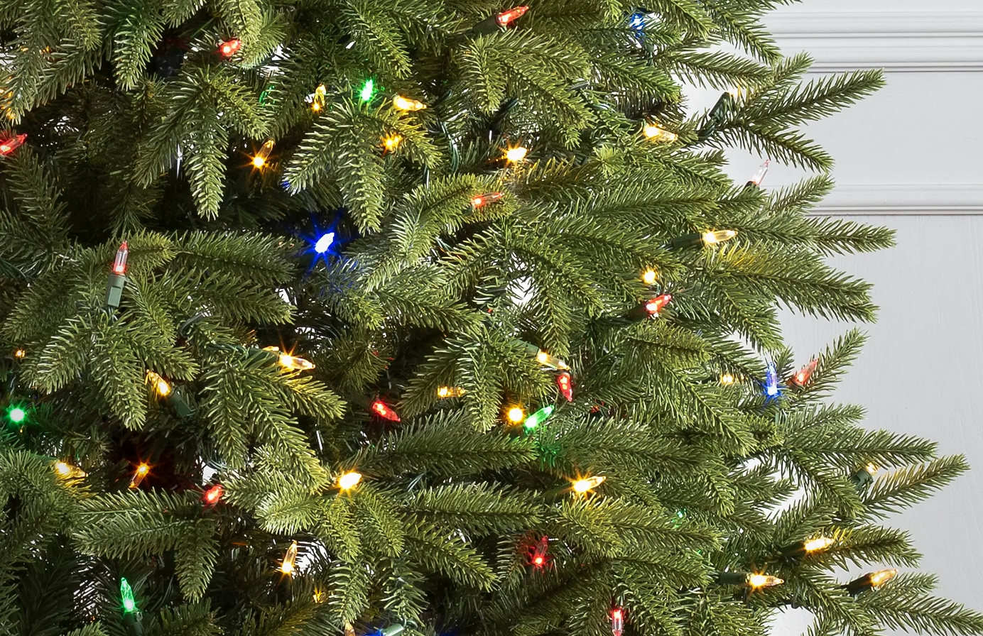 Close-up of artificial Christmas tree branches with multicolored lights.