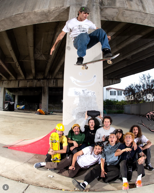 Jacuzzi team huddle together with skateboarder olling over them