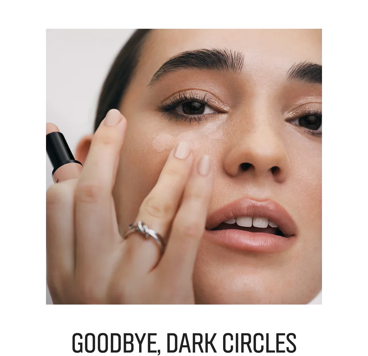 Close-up of a woman applying Skin Corrector Stick under her eye, with title 'Goodbye, Dark Circles' below.